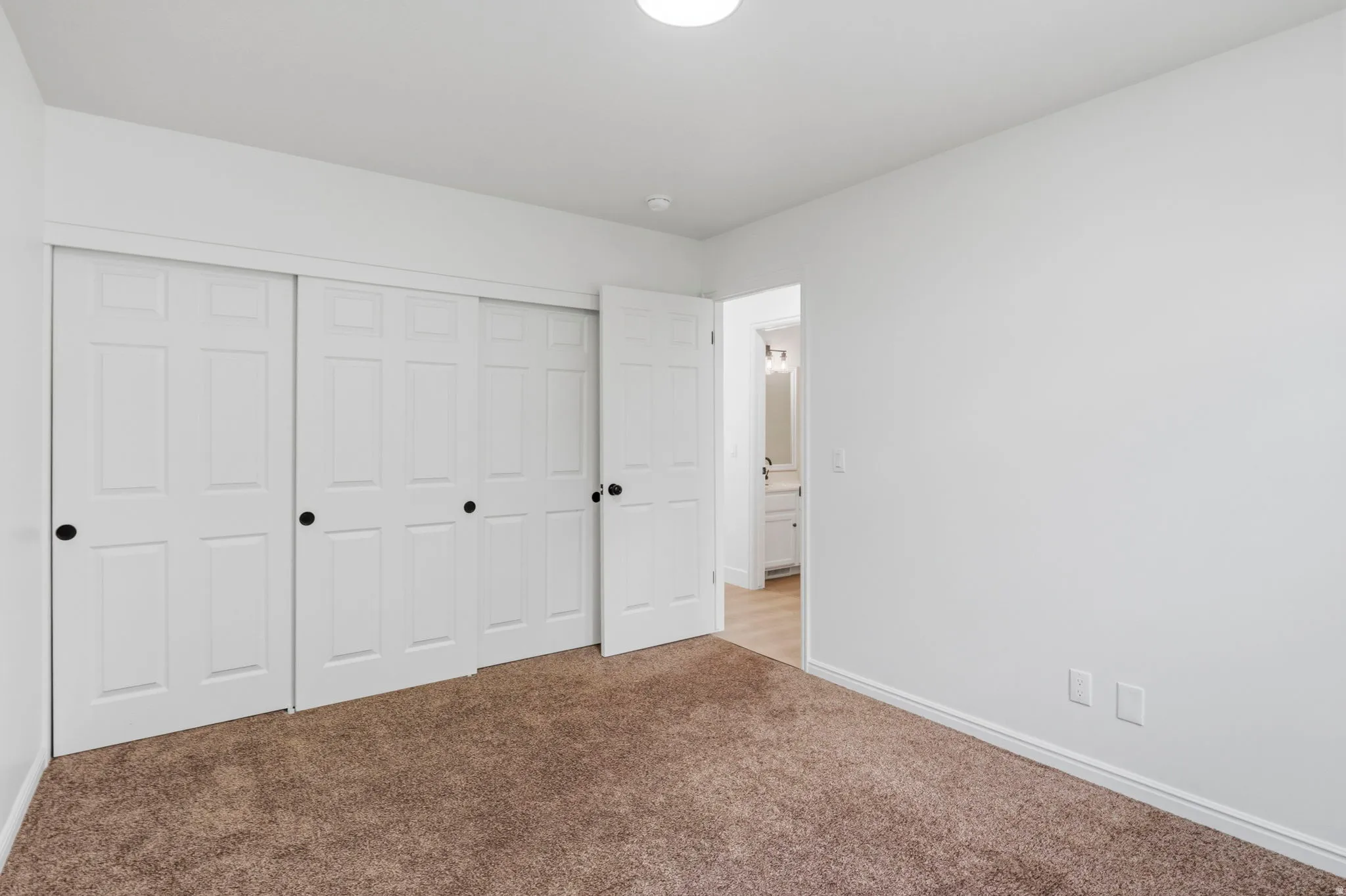 Room featuring white walls, brown carpet flooring, and a semi-flush mount ceiling light
