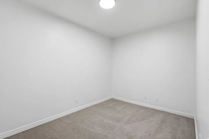Recessed lighting, light gray carpeting, and white wall finishes