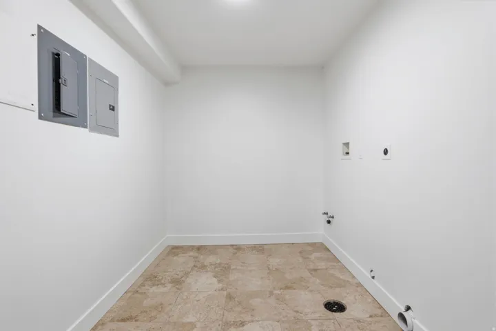 Utility room featuring neutral-toned floor tile and white baseboards