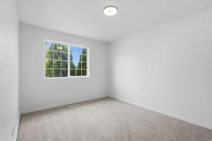 White walls, gray carpet, and a window with white grilles