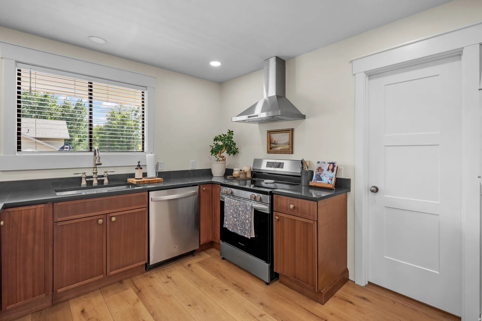 Kitchen featuring wood-finish flooring, dark countertops, stainless steel appliances, and wood cabinetry