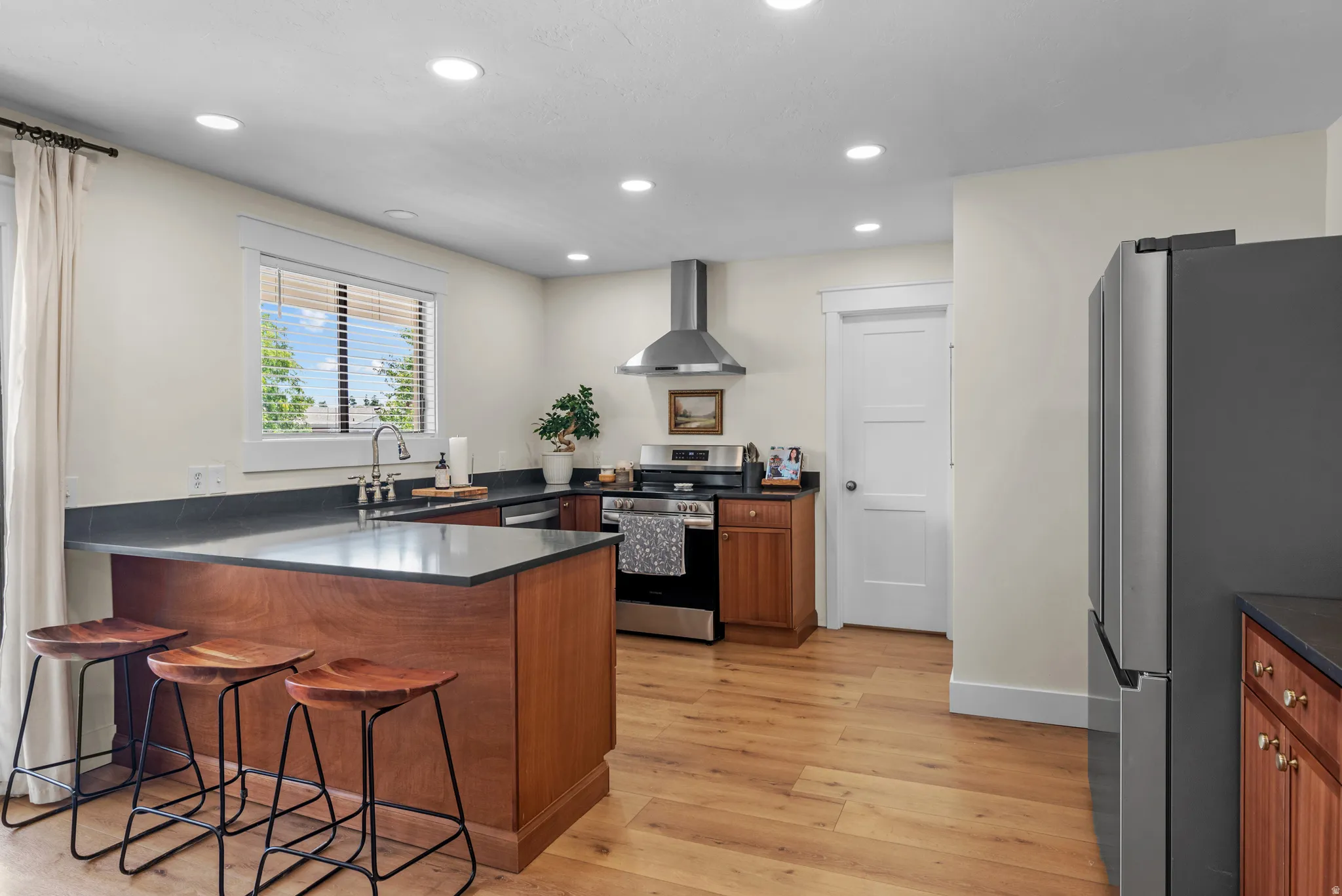 Kitchen featuring a wood-finish island with seating, stainless steel appliances, recessed lighting, wood-finish flooring, and dark countertops