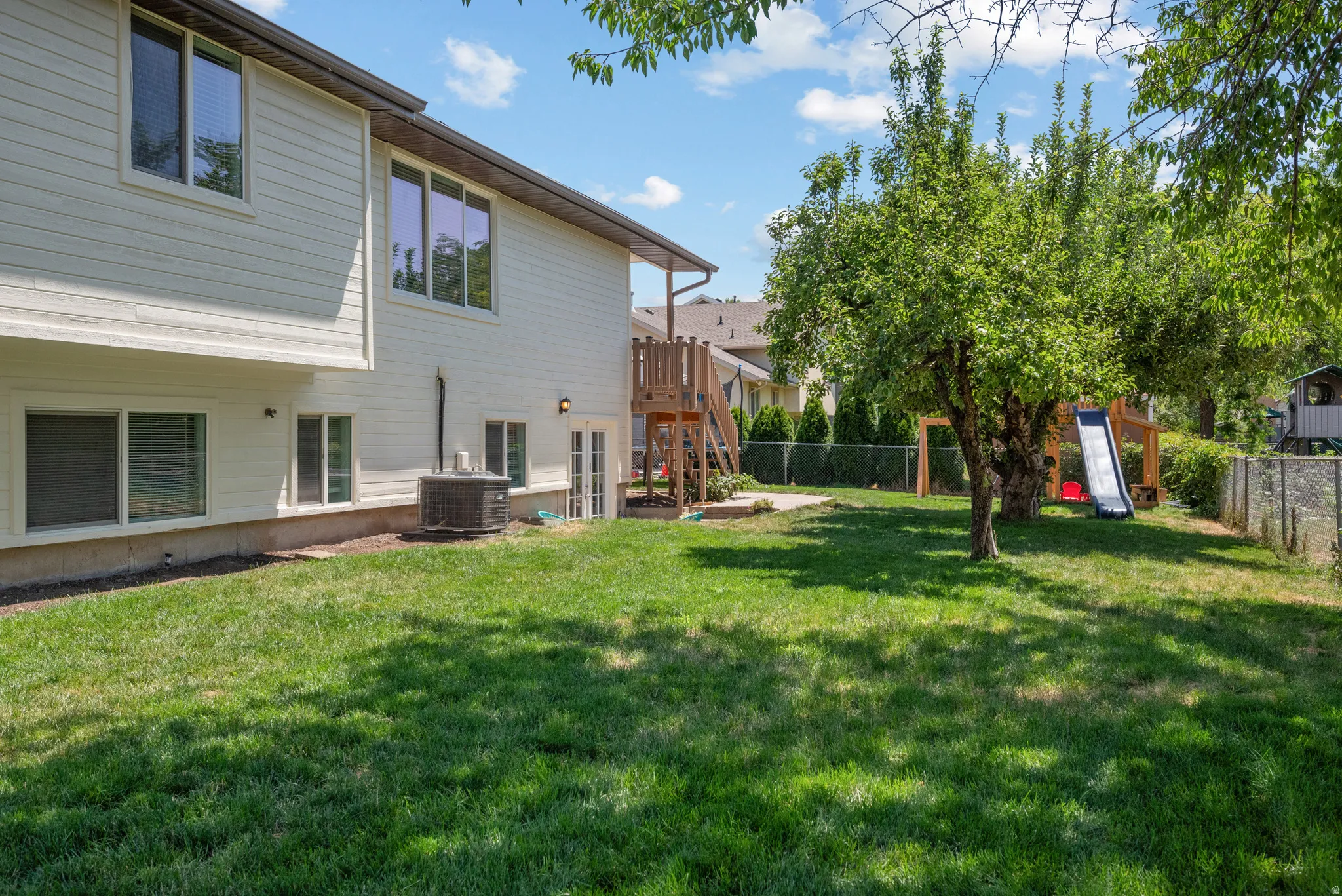 Spacious backyard featuring a manicured lawn, mature trees