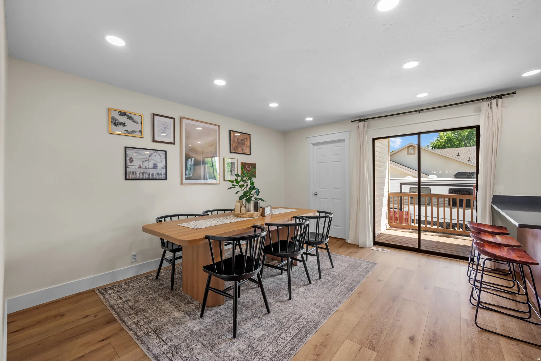 Dining area featuring recessed lighting, light wood-finish flooring, and a sliding glass door opening to an outdoor deck
