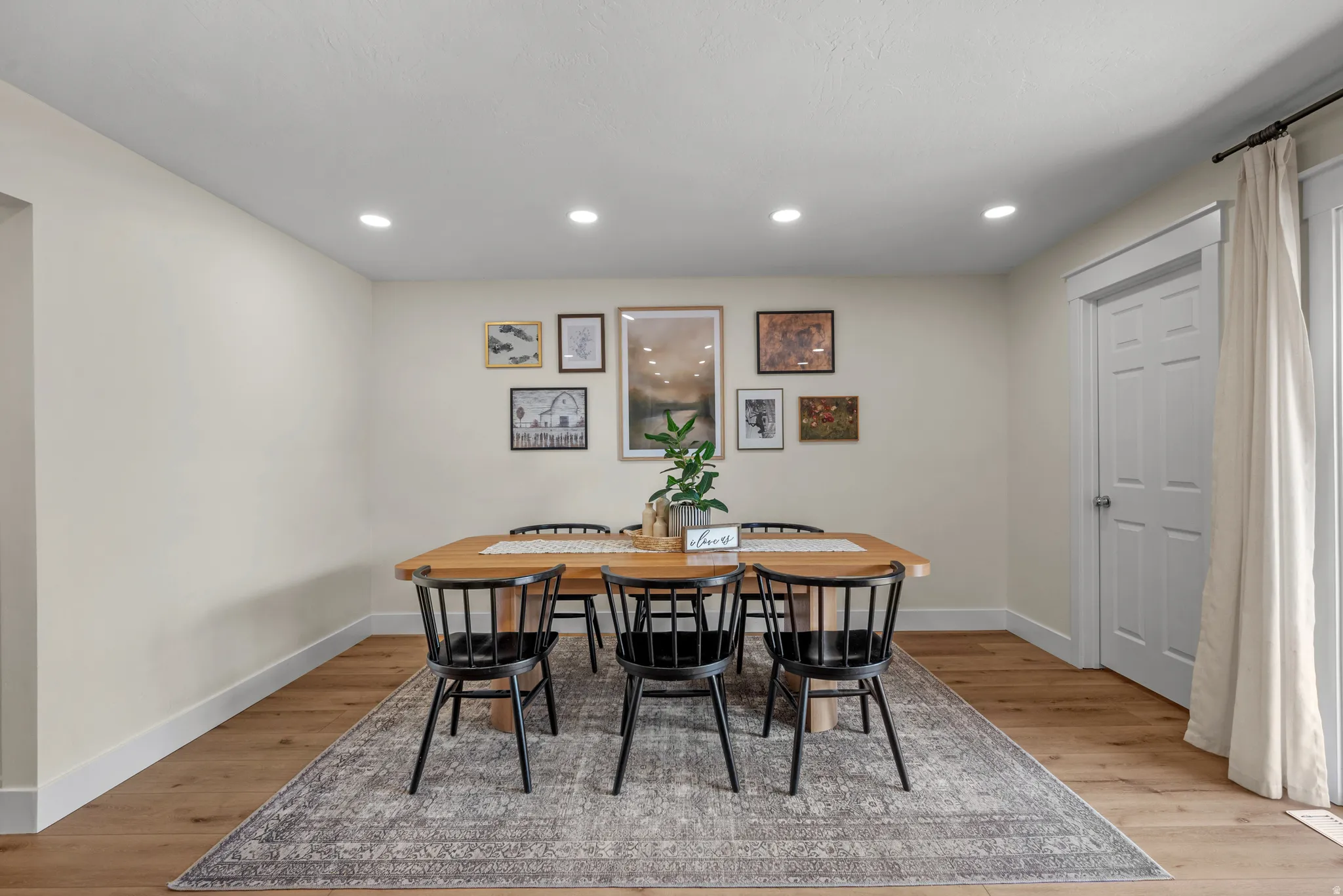 Dining space featuring recessed lighting, wood-finish flooring, white baseboards, and a paneled door