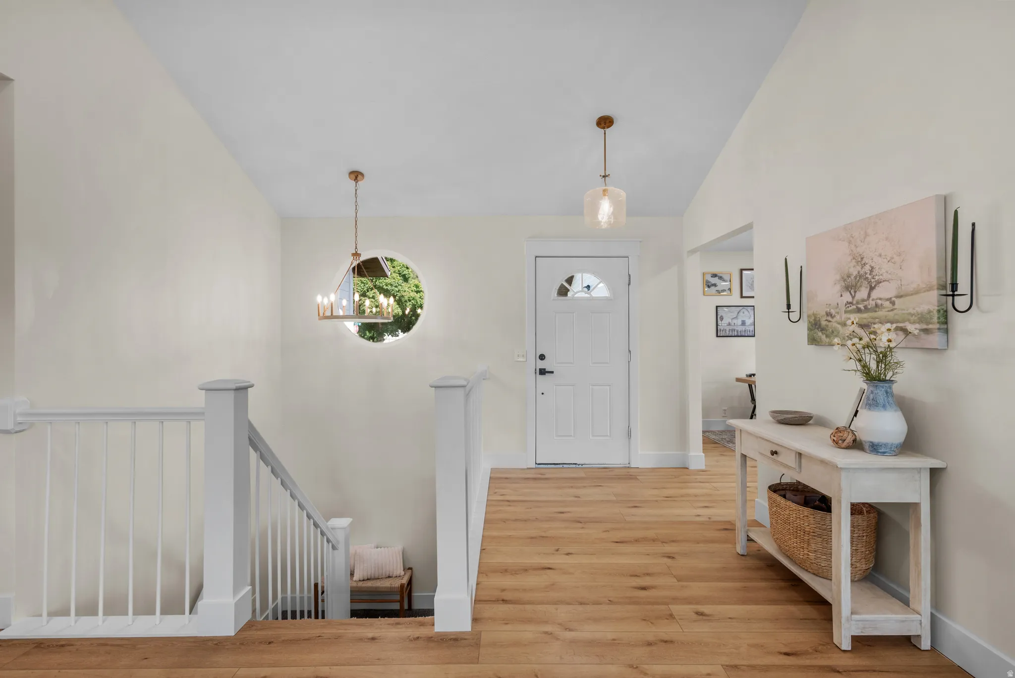 Light wood-finish flooring extends through this entryway, featuring a white paneled door with an arched window