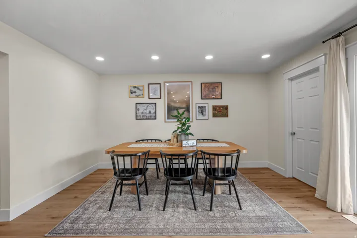 Dining space featuring recessed lighting, wood-finish flooring, white baseboards, and a paneled door