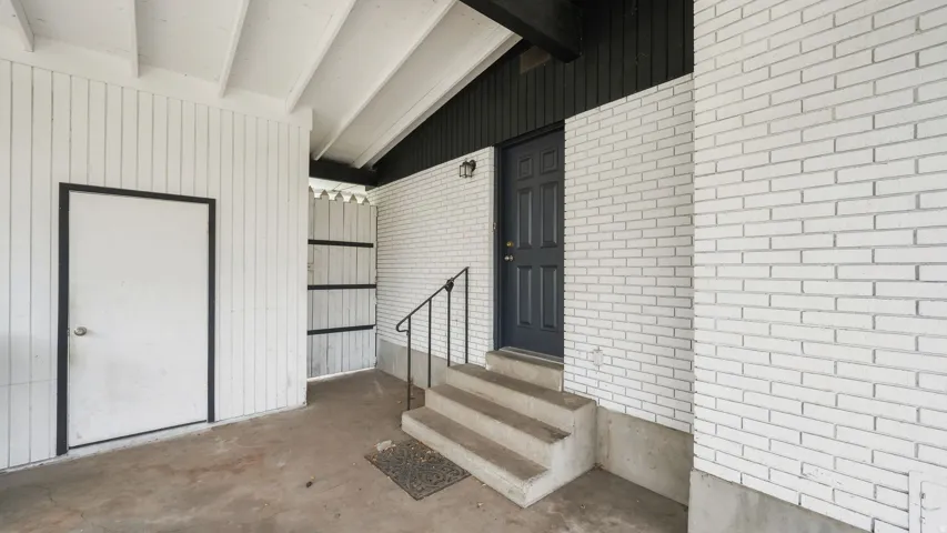 Entryway featuring white painted brick and vertical plank siding