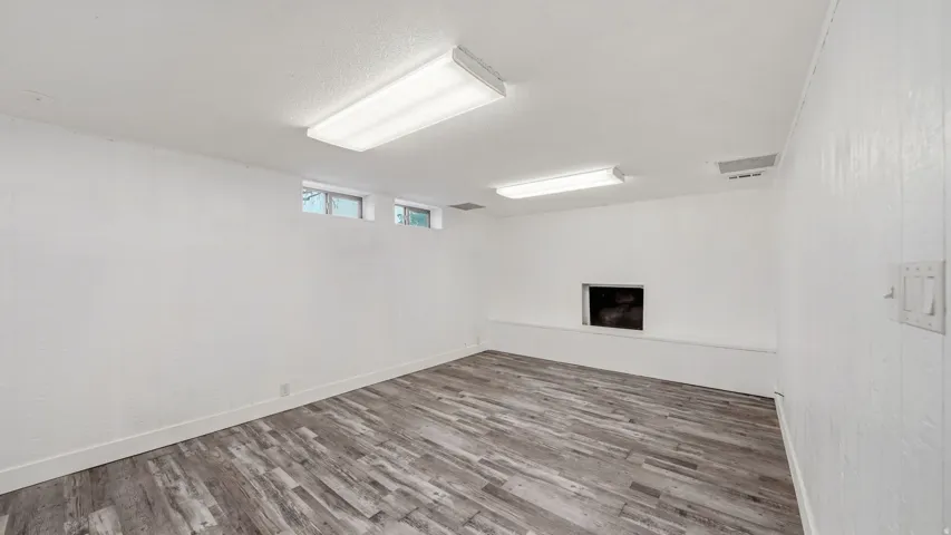 Spacious room featuring wood-finish flooring and white walls