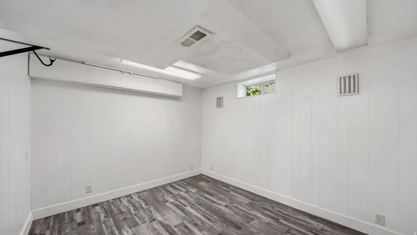 Room featuring vertical paneling walls, wood-finish flooring, and a single window