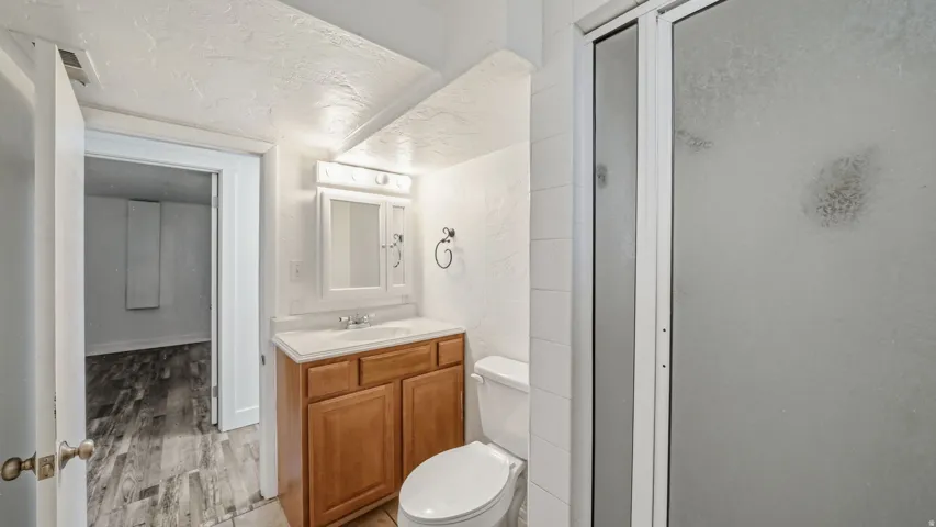 Bathroom featuring a wood-finish vanity with an integrated sink, a medicine cabinet with mirror, and a toilet