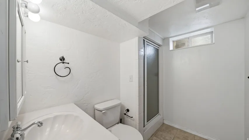 Bathroom featuring a single vanity, a toilet, and a glass-enclosed shower