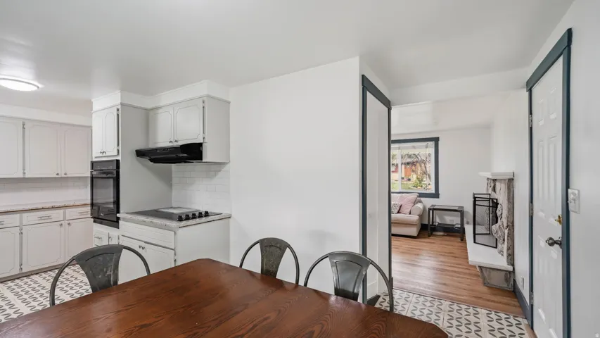 Bright kitchen featuring grey cabinetry, white subway tile backsplash, built-in double ovens, and a flat-top electric range