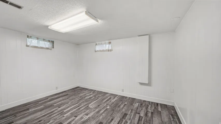 Room with white paneled walls, two windows, and wood-finish flooring