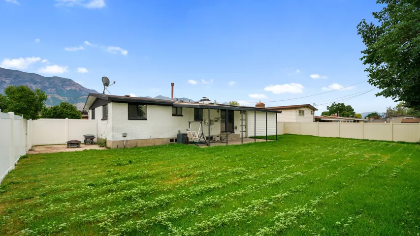 Expansive backyard featuring a privacy fence, covered patio, and mountain backdrop