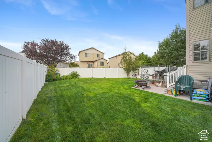 Expansive backyard featuring a lush green lawn, full privacy fencing, and a concrete patio space