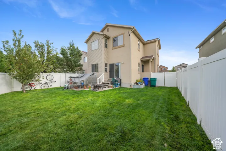 Expansive backyard featuring a manicured lawn, full privacy fencing, and a concrete patio