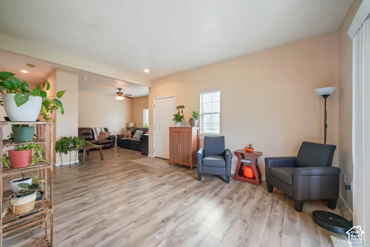 Spacious living area featuring light wood-finish flooring, neutral wall tones, recessed lighting, and a white paneled door