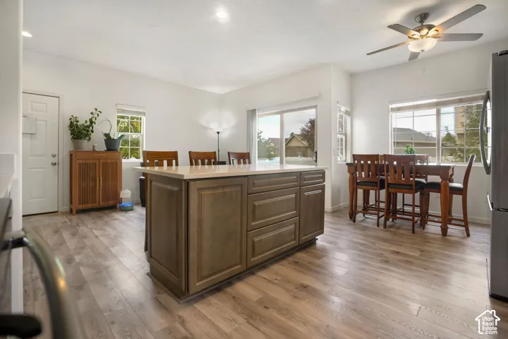 Kitchen featuring a central island with countertop, wood-finish flooring, white walls, and multiple windows