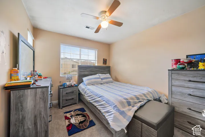 Carpeted bedroom featuring a vaulted ceiling and a ceiling fan with integrated lighting