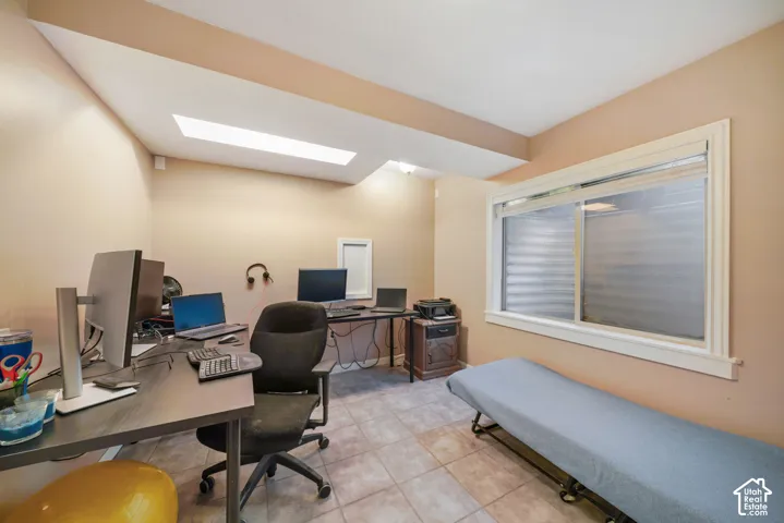 Versatile room featuring two skylights, tiled flooring, and a large window with white trim