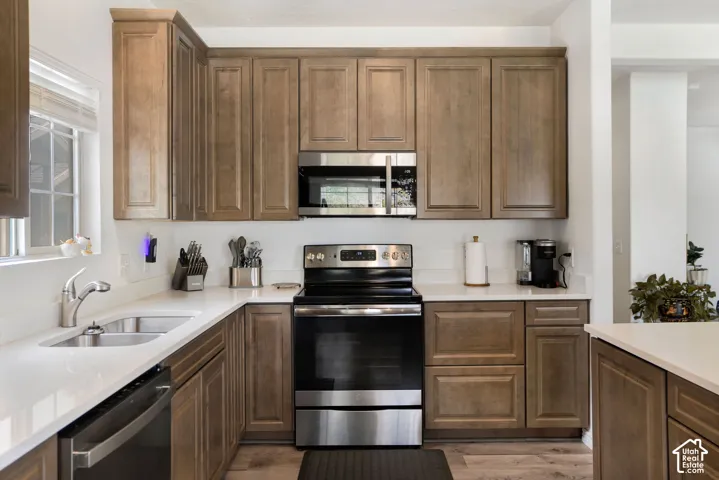 Full kitchen featuring wood-finish cabinetry, white countertops, and stainless steel appliances including a range, microwave, and dishwasher