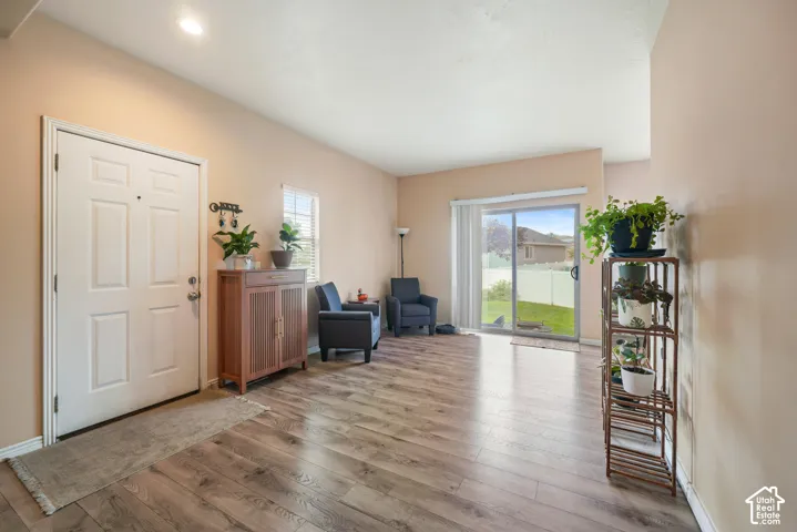 Spacious living area featuring wood-finish flooring, a white paneled entry door, and recessed lighting