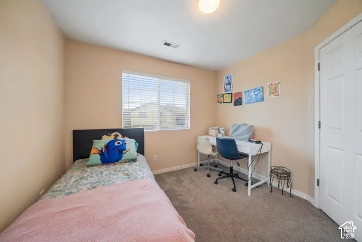 Carpeted room featuring neutral wall tones, a window with horizontal blinds, a white paneled door, and a ceiling-mounted light fixture