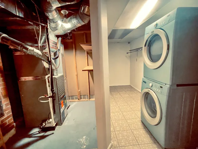 Laundry area featuring a stacked washer and dryer, tiled flooring, and a clothes hanging rod