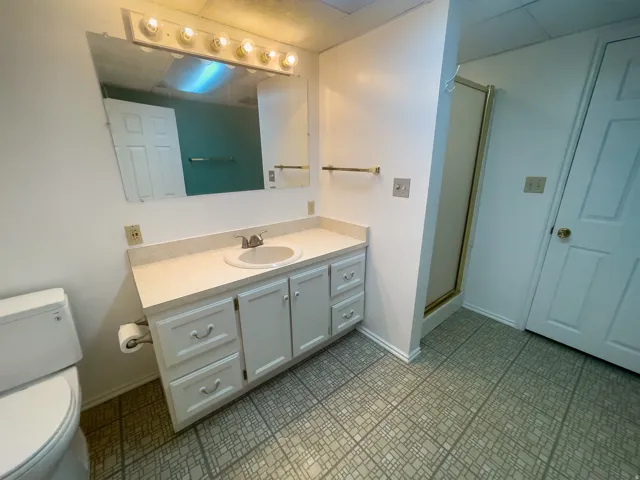 Bathroom vanity with a single basin sink, white cabinetry, and a light-colored countertop