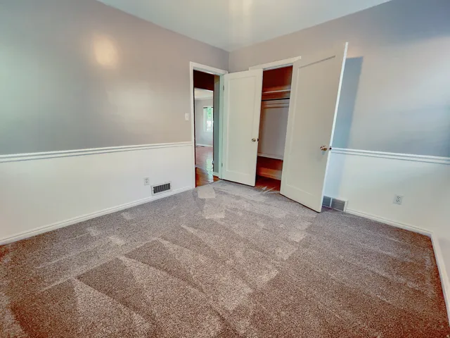 Neutral-toned carpeting paired with a two-tone wall treatment featuring chair rail molding