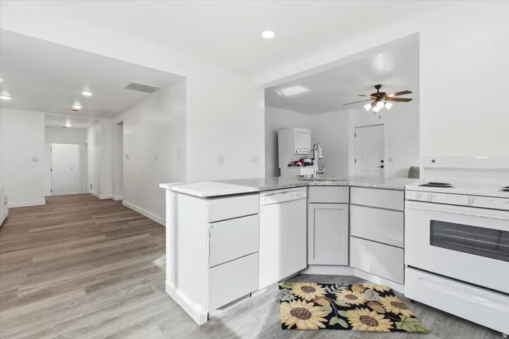 Open-concept kitchen featuring white cabinetry, light-toned countertops, and a full suite of white appliances