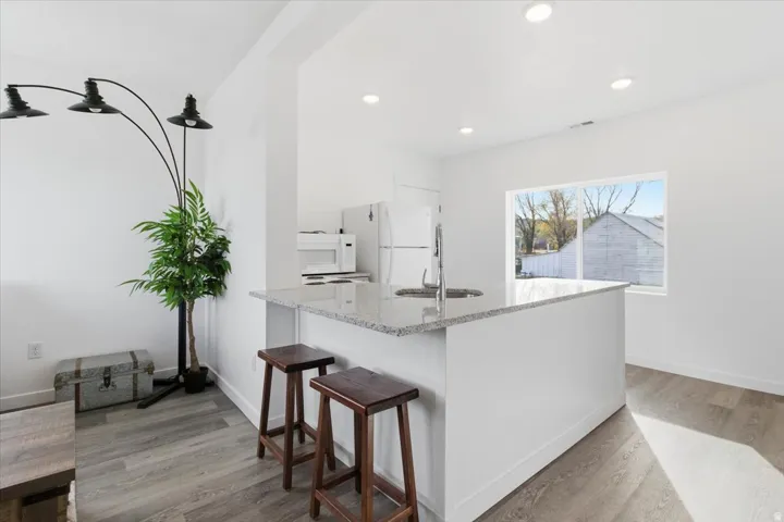 Kitchen island featuring a stainless steel sink, granite countertop, and white cabinetry