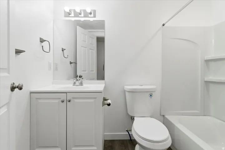 Bathroom featuring a white vanity with integrated sink, chrome faucet, and overhead bar lighting