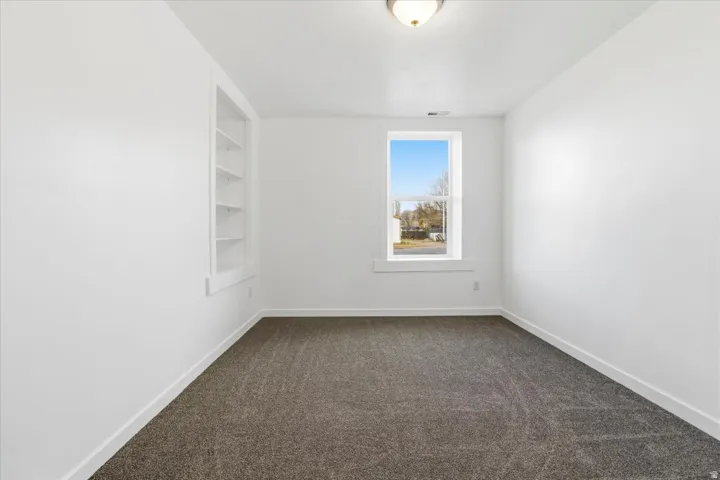 Bright interior space featuring a built-in shelving unit, white trim, and a window with a streetscape beyond
