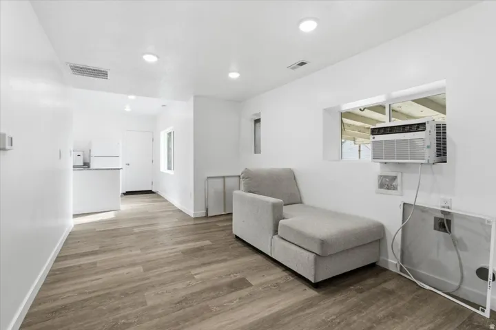 Open-concept living area with wood-finish flooring, recessed lighting, and white baseboards