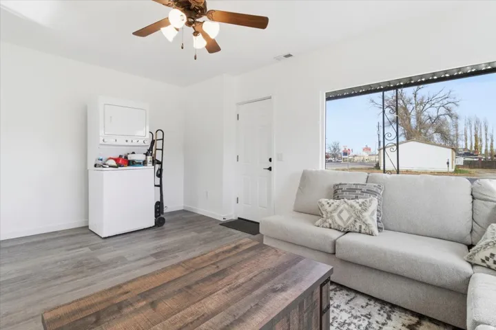 Interior space featuring wood-finish flooring, white walls, and a ceiling fan with integrated lighting