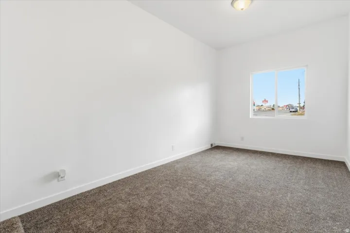 Carpeted room with a double-paned window, white walls, and white baseboards