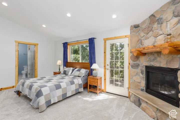 Stone-clad fireplace with a wood mantel, glass-paneled exterior door, window with wood trim, recessed lighting, and wood-trimmed doorway