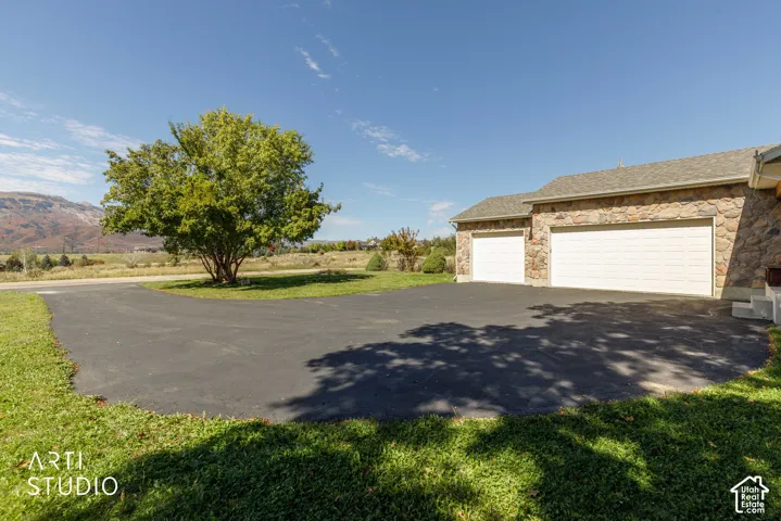 Stone exterior with a two-car garage, an additional single-car garage, and an asphalt driveway