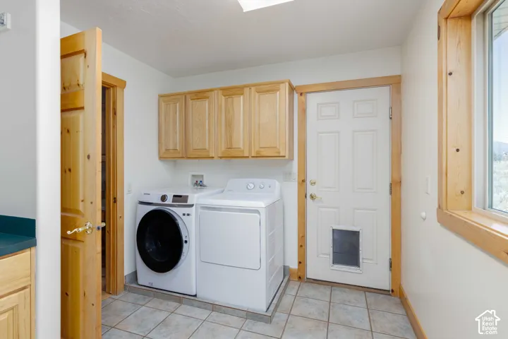 Laundry area featuring tile flooring, wood-finish cabinetry, and a window with wood-finish trim