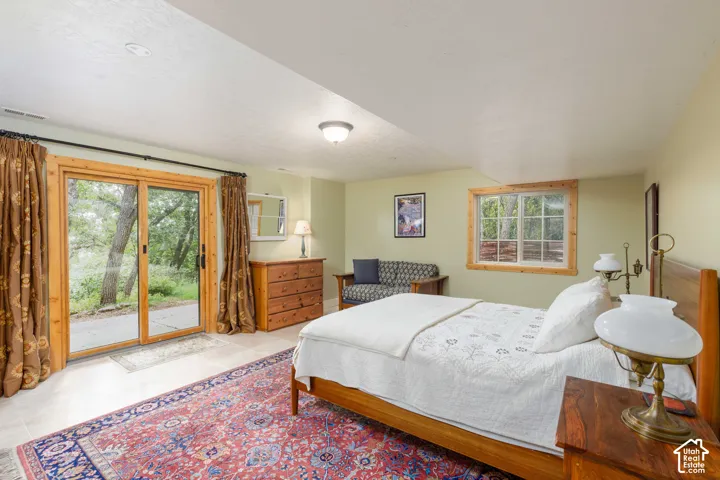 Bedroom featuring a large sliding glass door with wood trim, a secondary window with wood trim, recessed ceiling lighting, and tile flooring