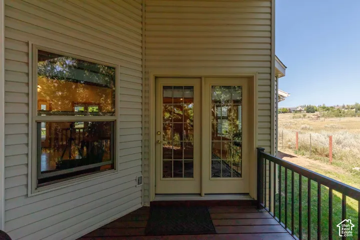 Wood-look deck flooring with black metal railings, leading to double glass-paneled doors