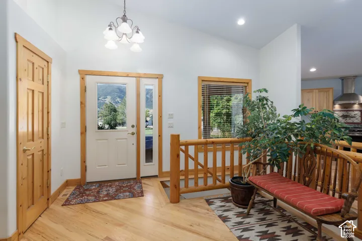 Vaulted ceilings, wood-finish flooring, natural wood door and trim, and a glass-paneled entry door with sidelight