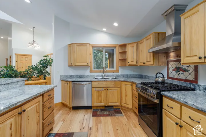 Kitchen featuring wood-finish flooring, wood cabinetry, stone countertops, stainless steel appliances, and a stainless steel range hood