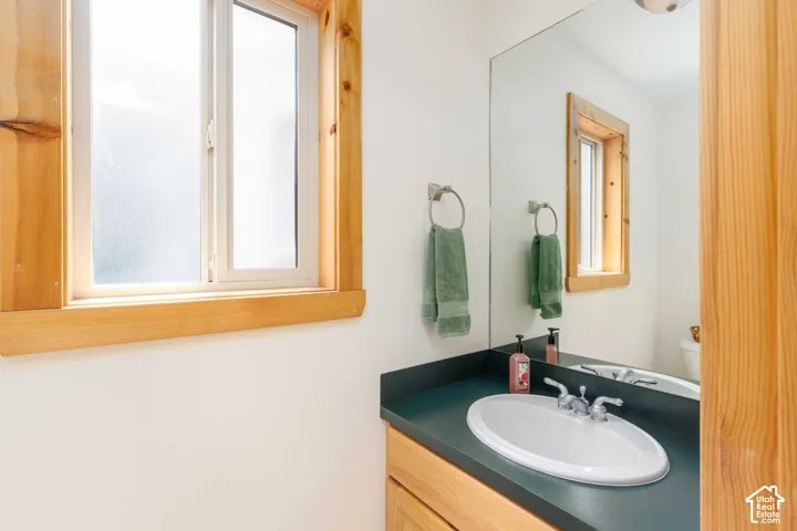 Bathroom vanity with an integrated oval sink, dark countertop, and an expansive wall-mounted mirror