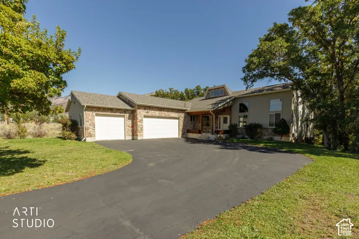 Stone veneer accents, multi-car garage, pitched roofline, dormer window, and mature trees