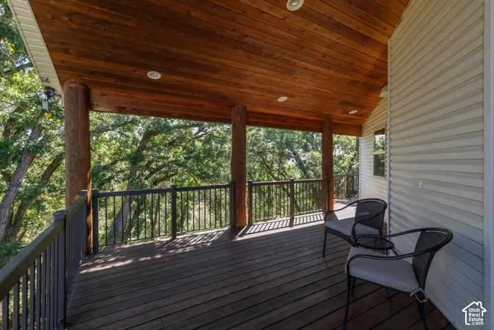 Covered outdoor deck with a wood-plank ceiling, recessed lighting, and log-style support columns