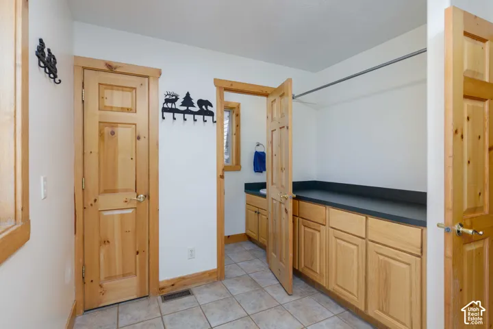 Wood-finish cabinetry with dark countertops, tile flooring, and wood-trim doorways