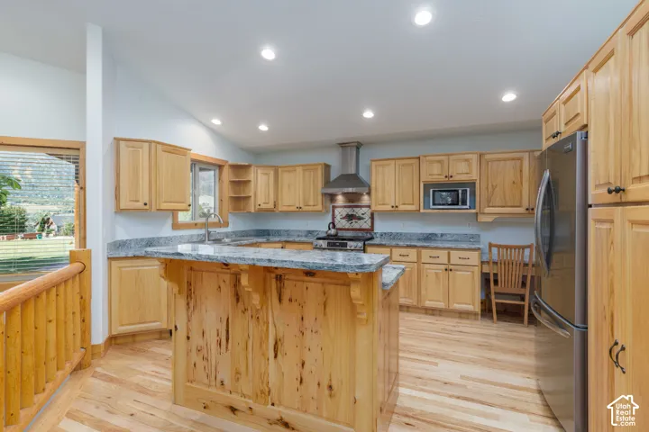 Kitchen featuring wood-finish flooring, natural wood cabinetry, a central island with a granite-style countertop, and stainless steel appliances